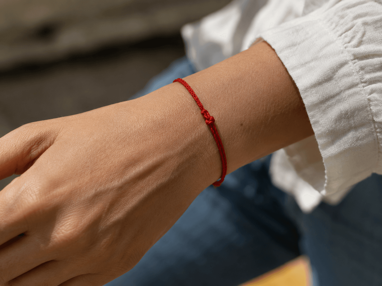 Close-up of a red protection bracelet tied around the wrist