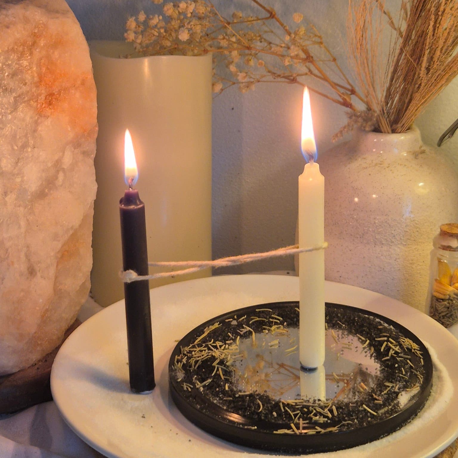 Black and white candles burning with an intact cord during a cord cutting ritual