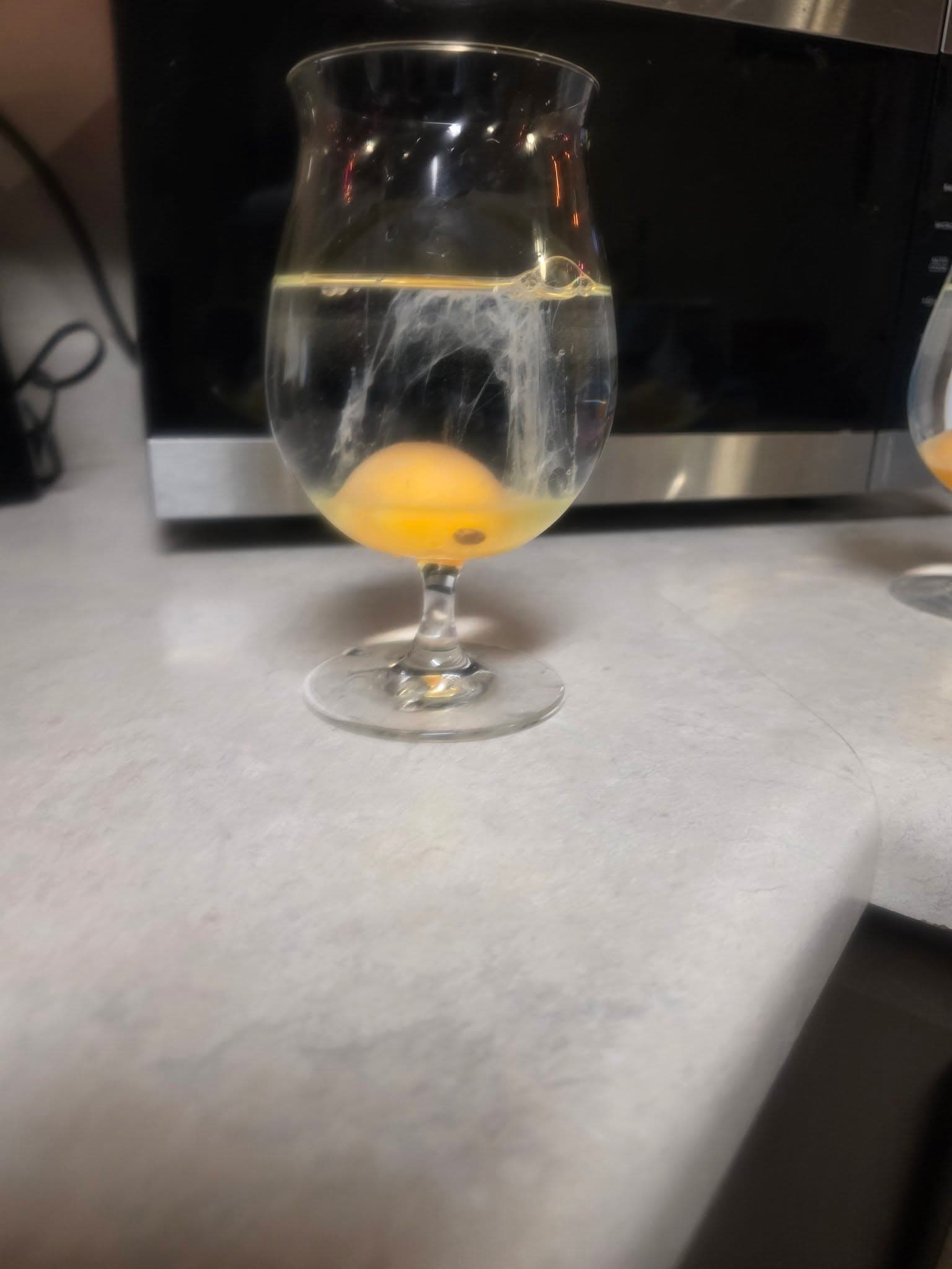 Egg cleanse showing strands rising through a clear glass of water